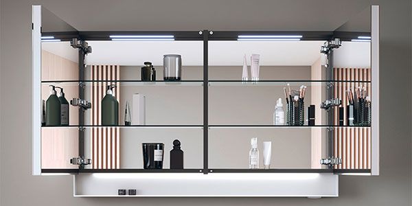 Ein Spiegelschrank mit integrierter Beleuchtung an den Seiten, der über einem Waschtisch hängt.
